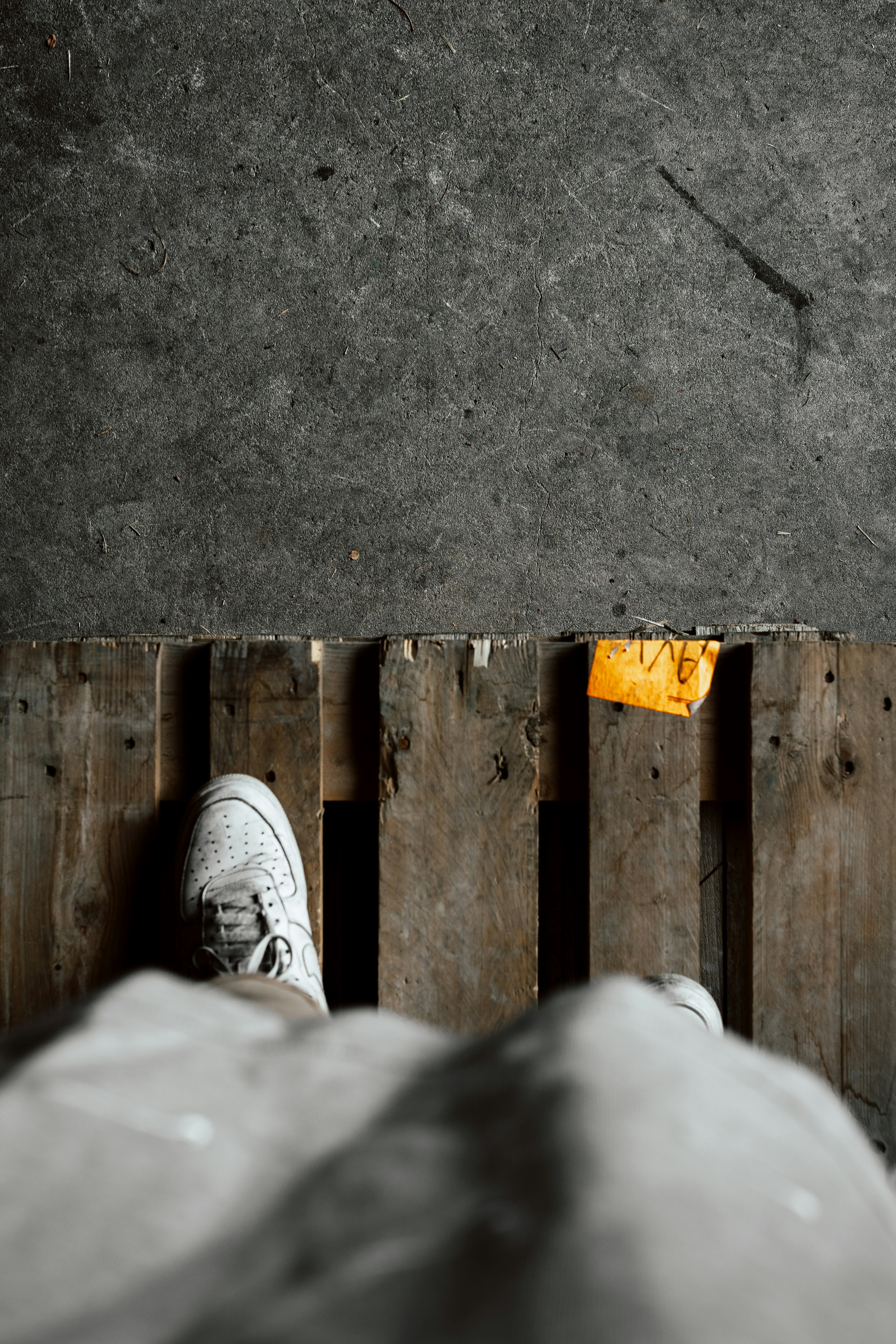 person in white pants and gray sneakers standing on gray concrete floor